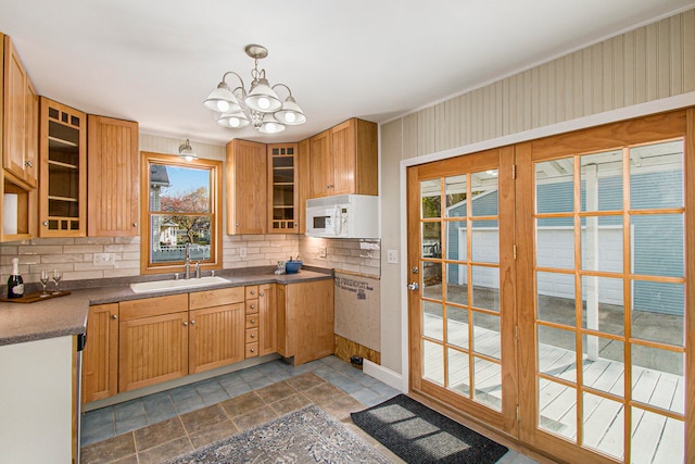 kitchen with tasteful backsplash, a chandelier, sink, and pendant lighting