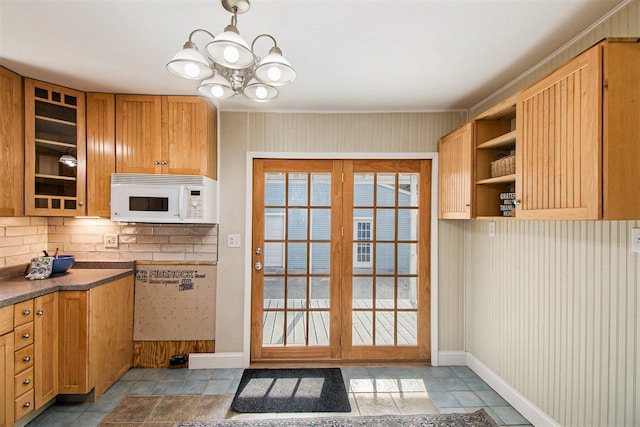 kitchen featuring an inviting chandelier, french doors, tasteful backsplash, and dark tile patterned floors