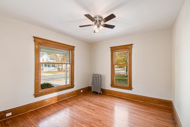 spare room with hardwood / wood-style floors, ceiling fan, and radiator