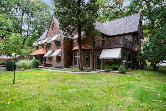 tudor-style house with a balcony and a front lawn