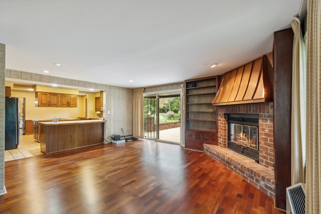 living room with light hardwood / wood-style flooring, a brick fireplace, and built in shelves