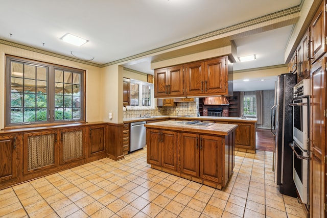 kitchen with ornamental molding, a kitchen island, stainless steel appliances, and tasteful backsplash