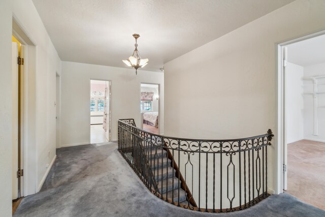 corridor featuring an inviting chandelier and carpet