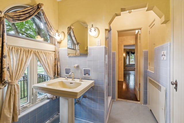 bathroom with tile walls, hardwood / wood-style floors, and radiator