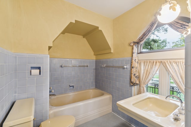 bathroom featuring a tub to relax in, toilet, tile patterned flooring, sink, and tile walls