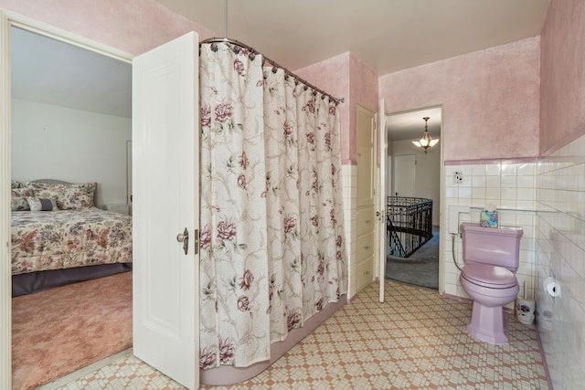 bathroom with toilet, tile walls, a chandelier, and a shower with curtain