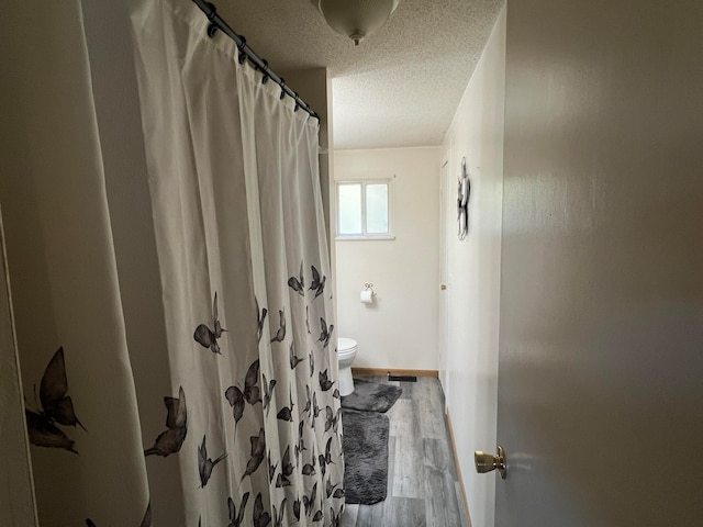 bathroom with hardwood / wood-style floors, a shower with curtain, a textured ceiling, and toilet