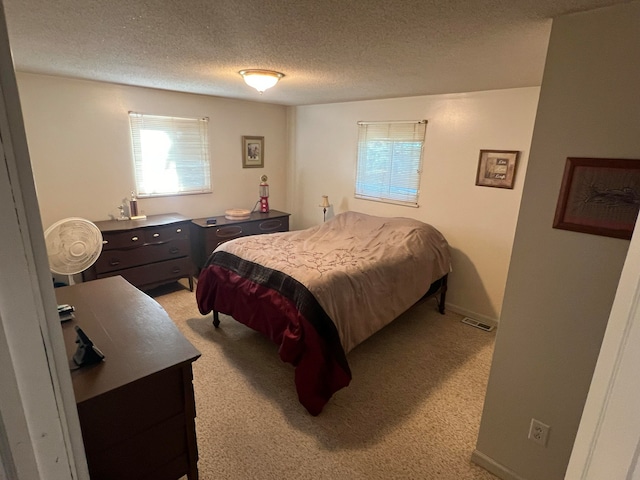 bedroom with light carpet and a textured ceiling