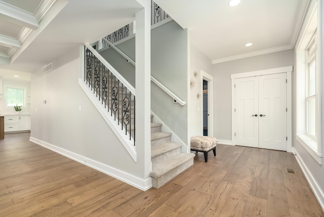 entryway with light hardwood / wood-style floors, crown molding, and plenty of natural light