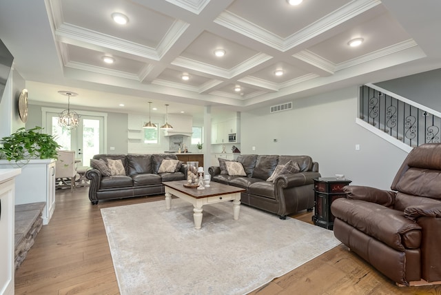 living room featuring a notable chandelier, coffered ceiling, beamed ceiling, and light wood-type flooring