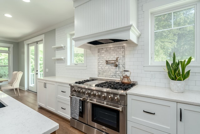 kitchen with range with two ovens, white cabinetry, light stone counters, ornamental molding, and dark hardwood / wood-style floors