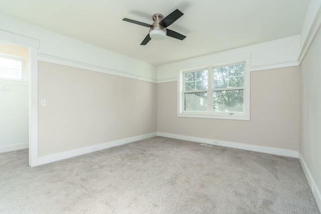 empty room with ceiling fan, a wealth of natural light, and light colored carpet