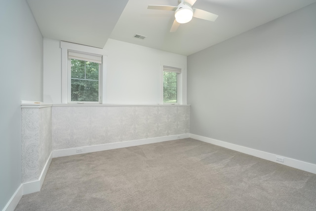 carpeted empty room featuring ceiling fan and a wealth of natural light