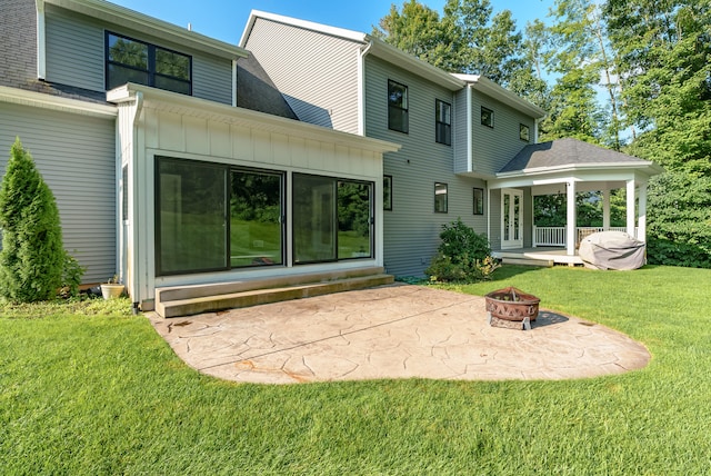 rear view of house with a patio, a lawn, and a fire pit