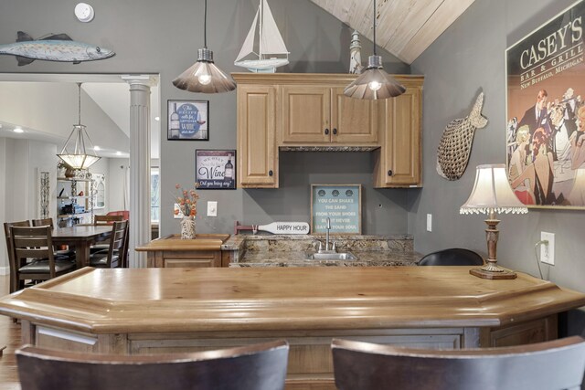 kitchen featuring ornate columns, light brown cabinetry, hanging light fixtures, and sink