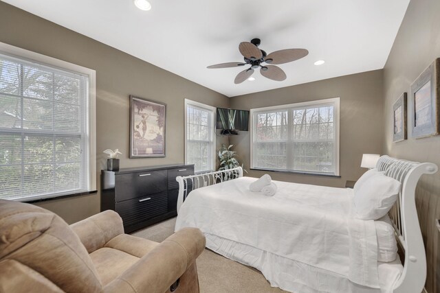 bedroom featuring light carpet, multiple windows, and ceiling fan