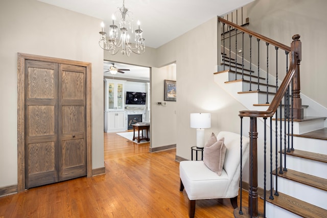 sitting room with hardwood / wood-style floors and ceiling fan with notable chandelier