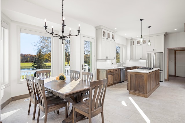 tiled dining room with an inviting chandelier, sink, and a water view