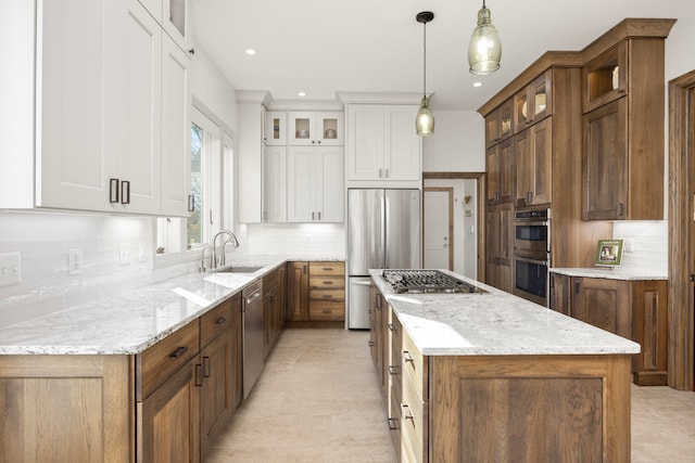 kitchen featuring appliances with stainless steel finishes, sink, backsplash, hanging light fixtures, and white cabinetry