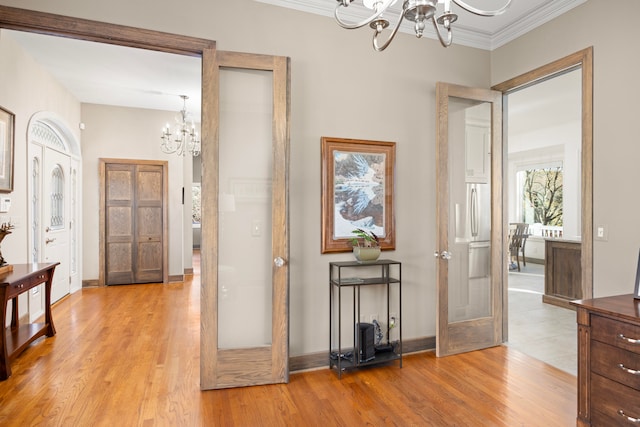 corridor with crown molding, a notable chandelier, light wood-type flooring, and french doors