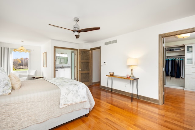 bedroom with a closet, ceiling fan, a spacious closet, and hardwood / wood-style floors