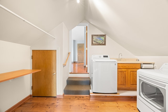 laundry area with sink, cabinets, light hardwood / wood-style flooring, and washing machine and clothes dryer