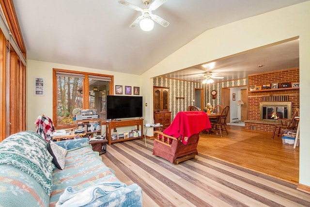 living room featuring a fireplace, wood-type flooring, vaulted ceiling, and ceiling fan