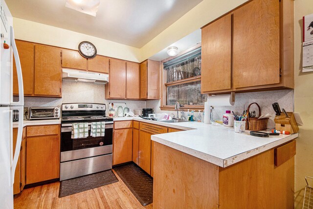 kitchen with kitchen peninsula, sink, stainless steel electric range, light wood-type flooring, and white refrigerator