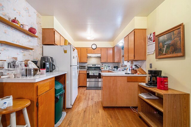 kitchen with kitchen peninsula, stainless steel electric range, a breakfast bar, light wood-type flooring, and white refrigerator