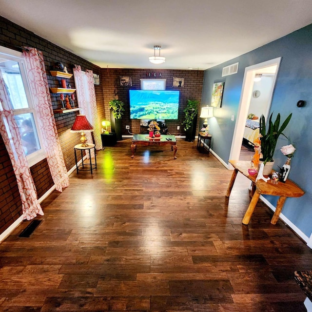 living room with brick wall and dark hardwood / wood-style flooring