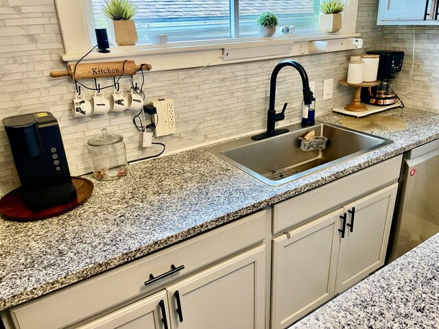 kitchen with white cabinetry, decorative backsplash, stainless steel dishwasher, and sink