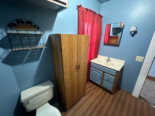 bathroom with wood-type flooring, toilet, and vanity