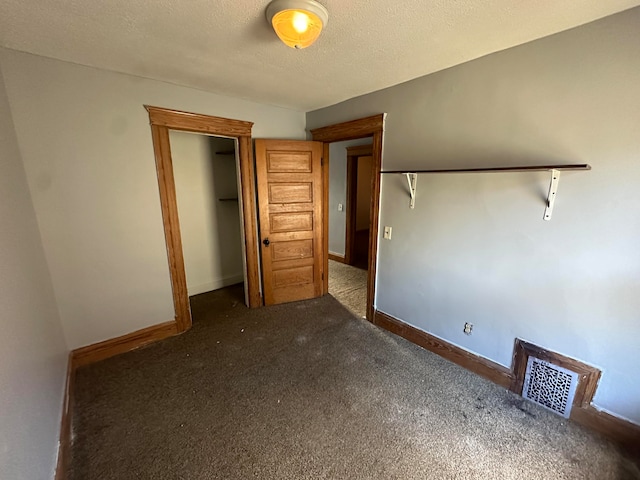 unfurnished bedroom with a textured ceiling and dark carpet