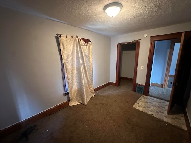 unfurnished bedroom featuring dark colored carpet and a textured ceiling