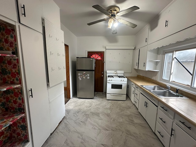 kitchen featuring white cabinets, sink, ceiling fan, white gas stove, and stainless steel fridge