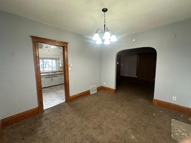 unfurnished dining area featuring dark colored carpet, a textured ceiling, and an inviting chandelier