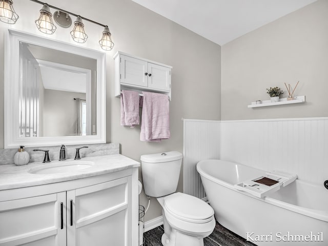 bathroom with a bathing tub, hardwood / wood-style flooring, vanity, and toilet