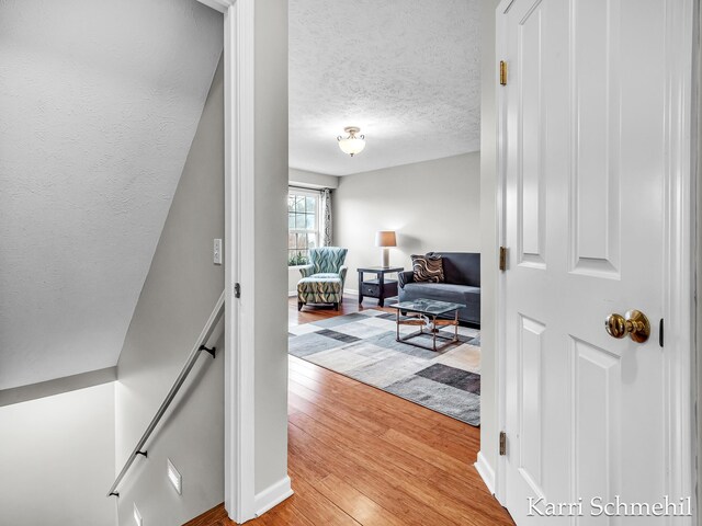 corridor with hardwood / wood-style floors and a textured ceiling