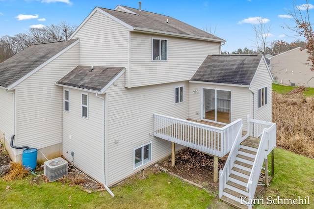 rear view of house featuring central air condition unit, a wooden deck, and a lawn