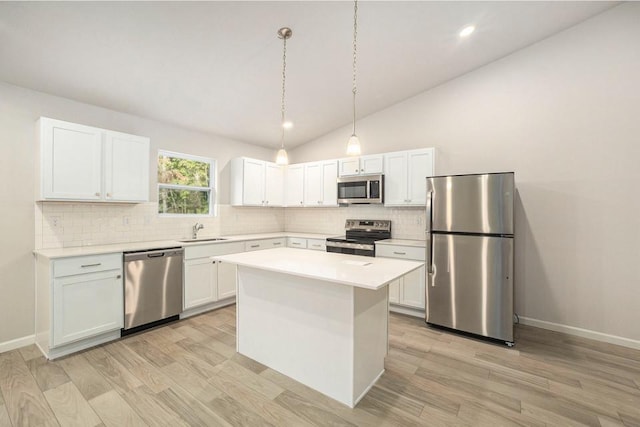 kitchen with lofted ceiling, a kitchen island, hanging light fixtures, white cabinets, and appliances with stainless steel finishes