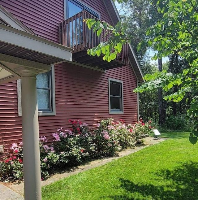 view of home's exterior featuring a balcony and a yard