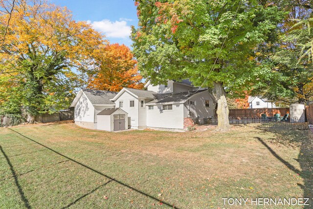 rear view of property featuring a lawn and a storage shed