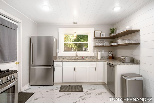 kitchen with appliances with stainless steel finishes, light stone counters, sink, pendant lighting, and white cabinetry