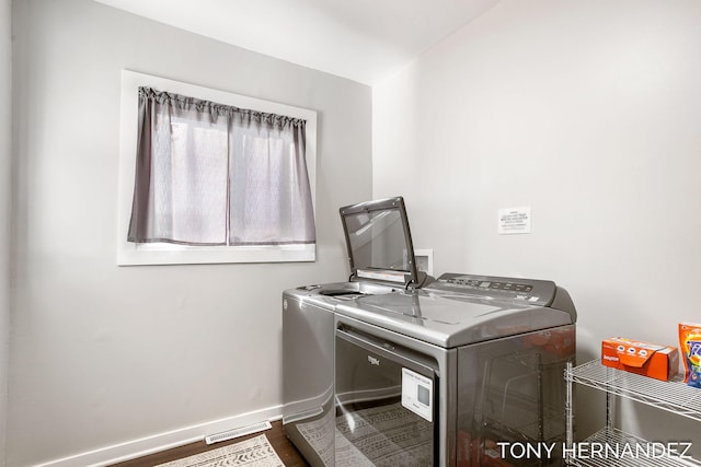 clothes washing area with washer and clothes dryer and hardwood / wood-style flooring