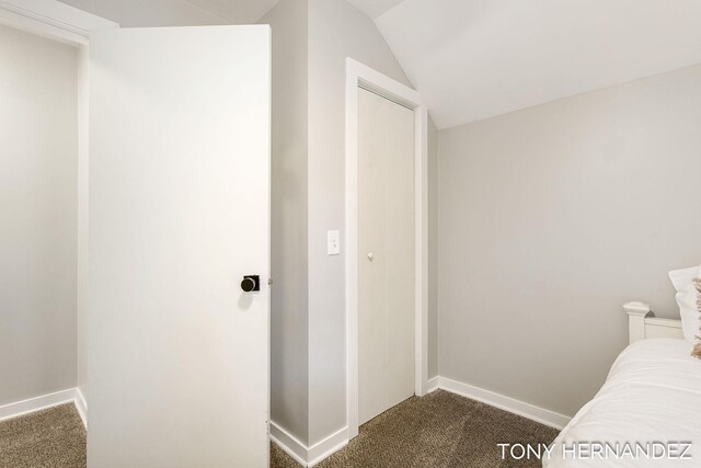 unfurnished bedroom featuring a closet, dark carpet, and vaulted ceiling