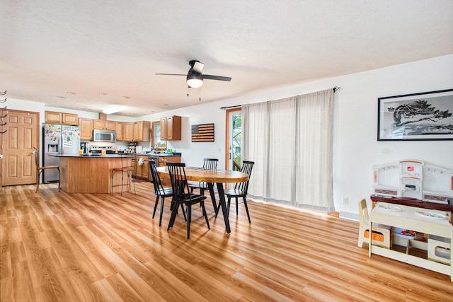 dining space with sink, a textured ceiling, light hardwood / wood-style floors, and ceiling fan