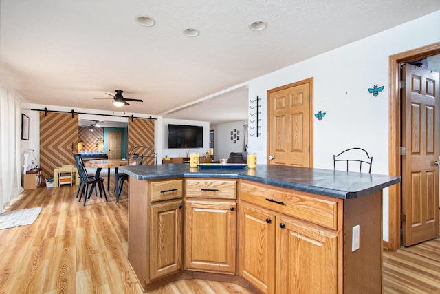 kitchen featuring a textured ceiling, a barn door, a center island, and light wood-type flooring