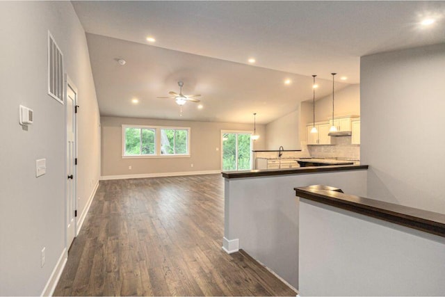 kitchen with lofted ceiling, decorative backsplash, white cabinetry, dark hardwood / wood-style floors, and pendant lighting