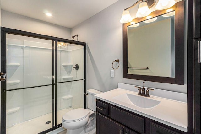 bathroom with a shower with door, vanity, and toilet