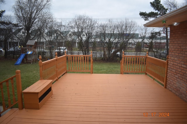 wooden deck with a playground and a lawn